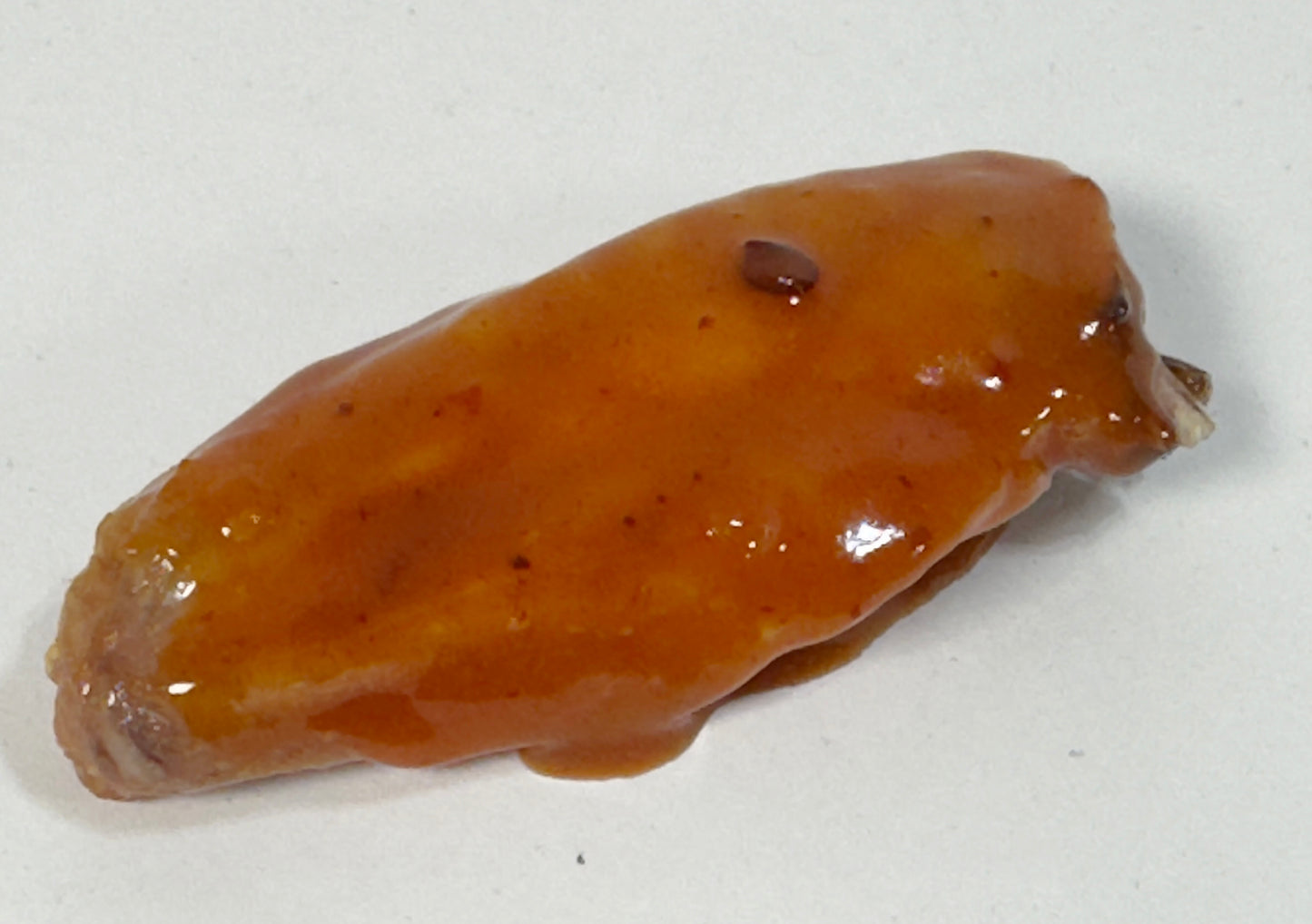 Chicken wing glazed with Mojo BBQ Hot Sauce close-up - Purple Pepper Farms sweet smoky BBQ sauce on wings