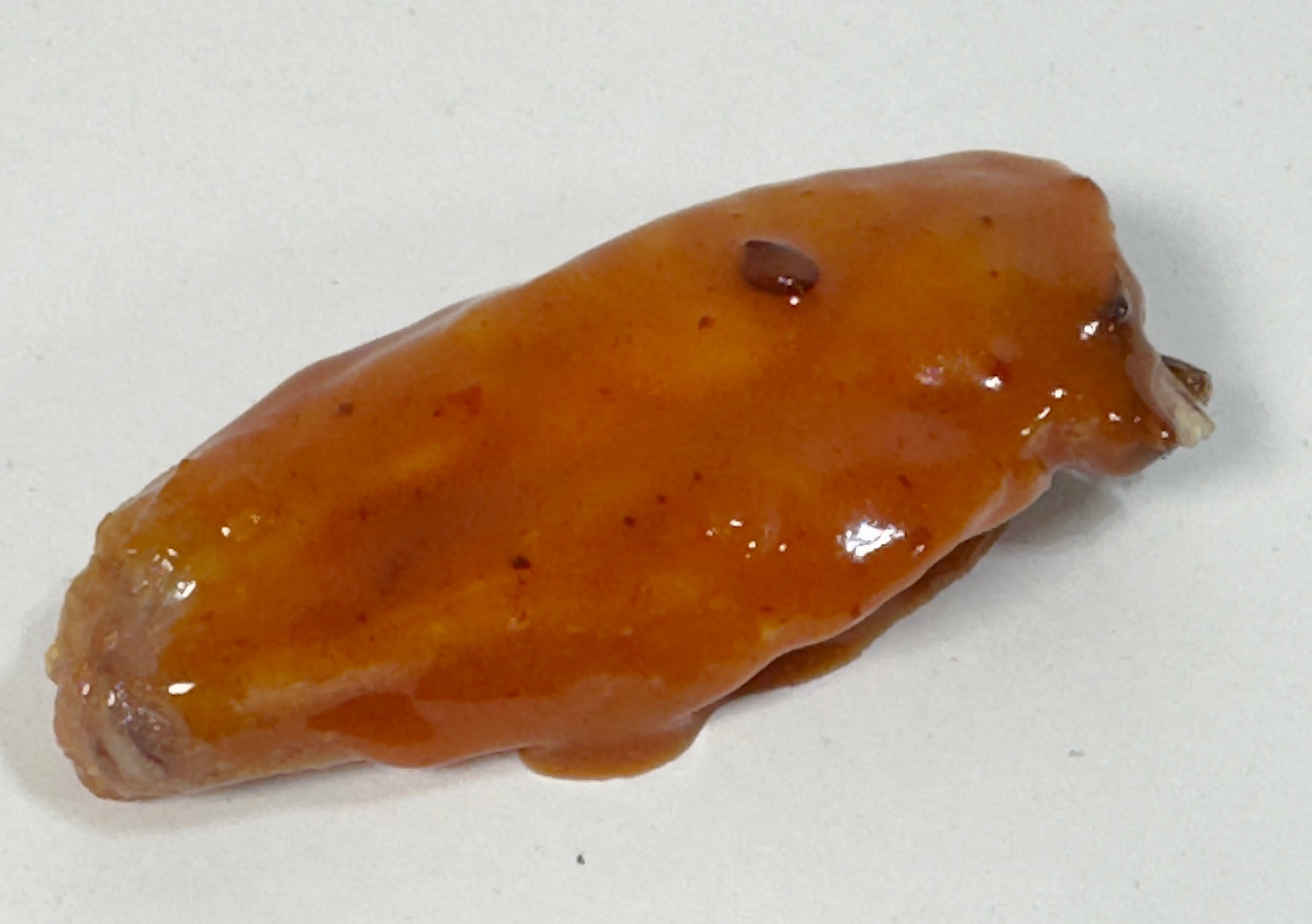 Chicken wing glazed with Mojo BBQ Hot Sauce close-up - Purple Pepper Farms sweet smoky BBQ sauce on wings