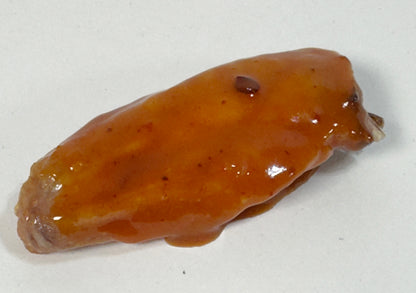 Chicken wing glazed with Mojo BBQ Hot Sauce close-up - Purple Pepper Farms sweet smoky BBQ sauce on wings
