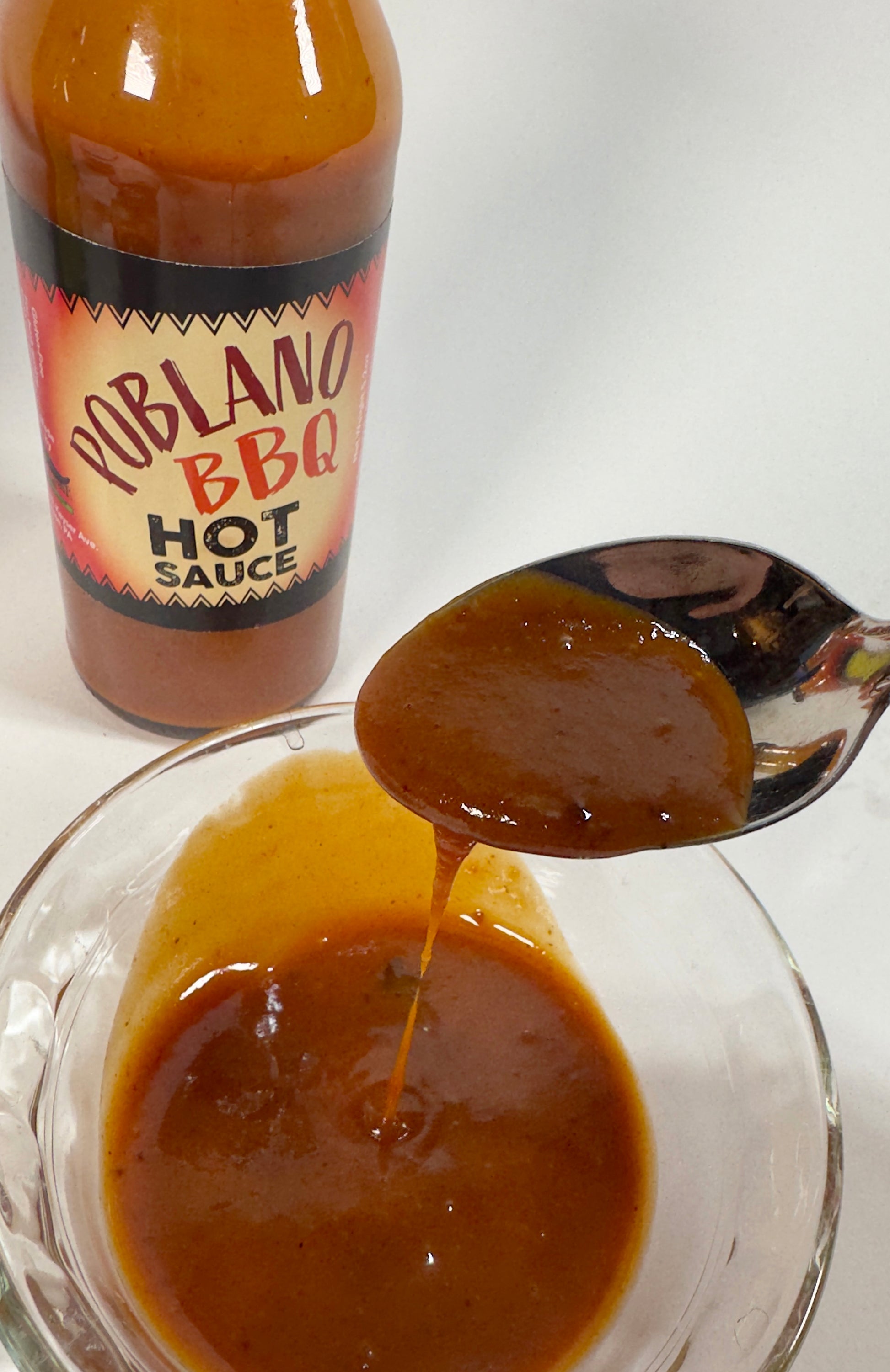 Poblano BBQ Hot Sauce poured on a spoon showing bold smoky texture - Purple Pepper Farms craft hot sauce