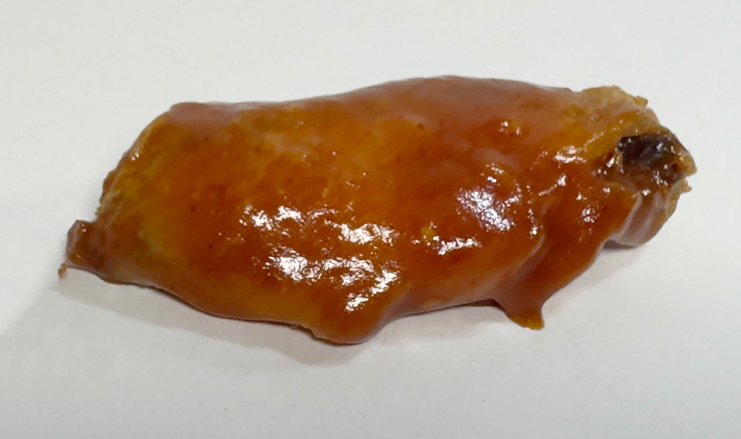 Chicken wing glazed with Poblano BBQ Hot Sauce close-up - Purple Pepper Farms smoky spicy BBQ sauce on wings