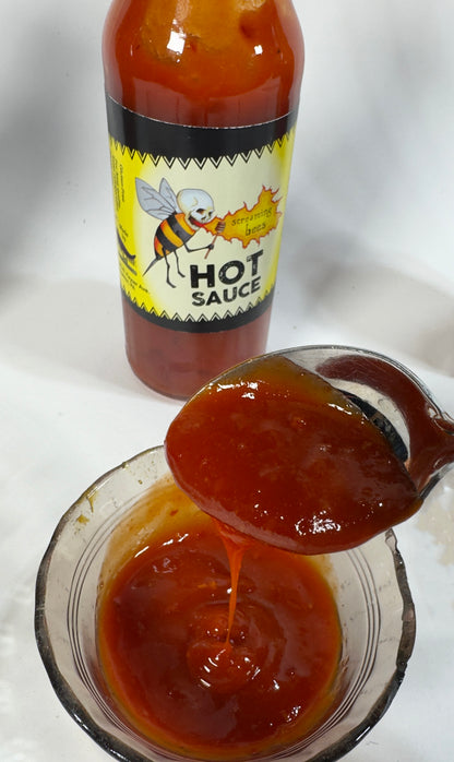 Screaming Bees Hot Sauce poured on a spoon showing fiery red texture - Purple Pepper Farms honey cayenne hot sauce