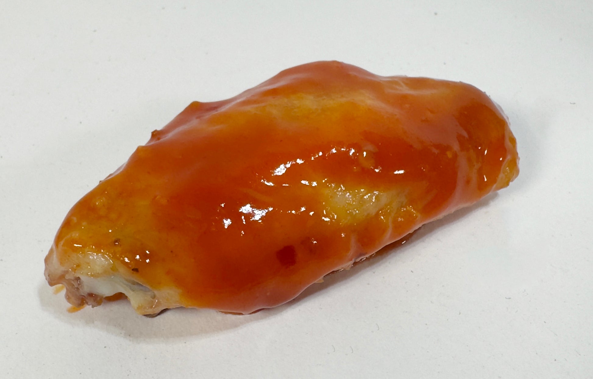Chicken wing glazed with Screaming Bees Hot Sauce close-up - Purple Pepper Farms honey cayenne hot sauce on wings
